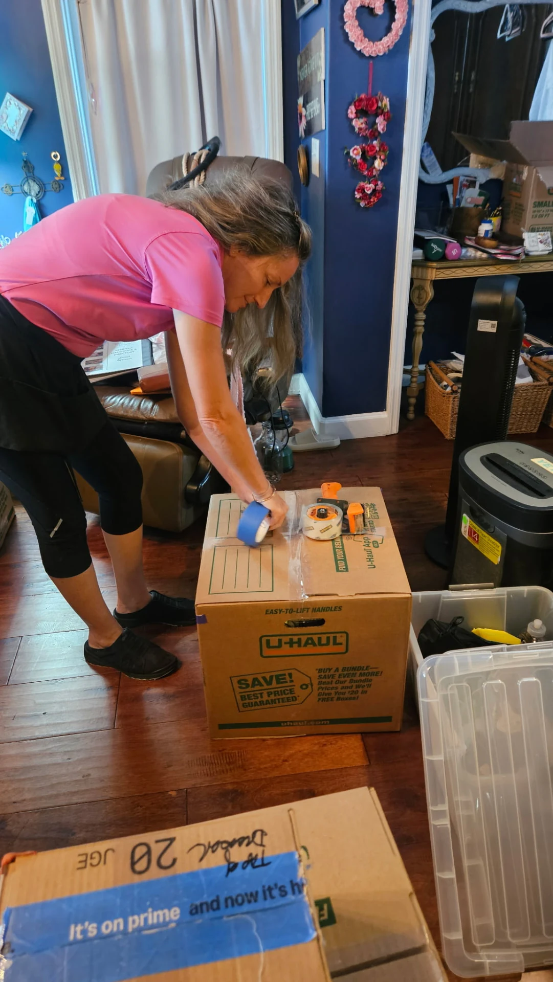 A Settled In by Tina team member sealing a moving box with tape