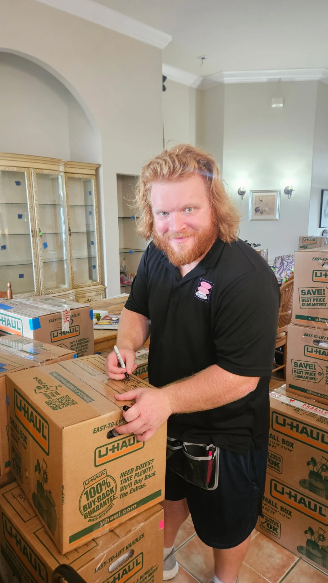 Jackson Leger labeling a moving box in his Settled In by Tina uniform